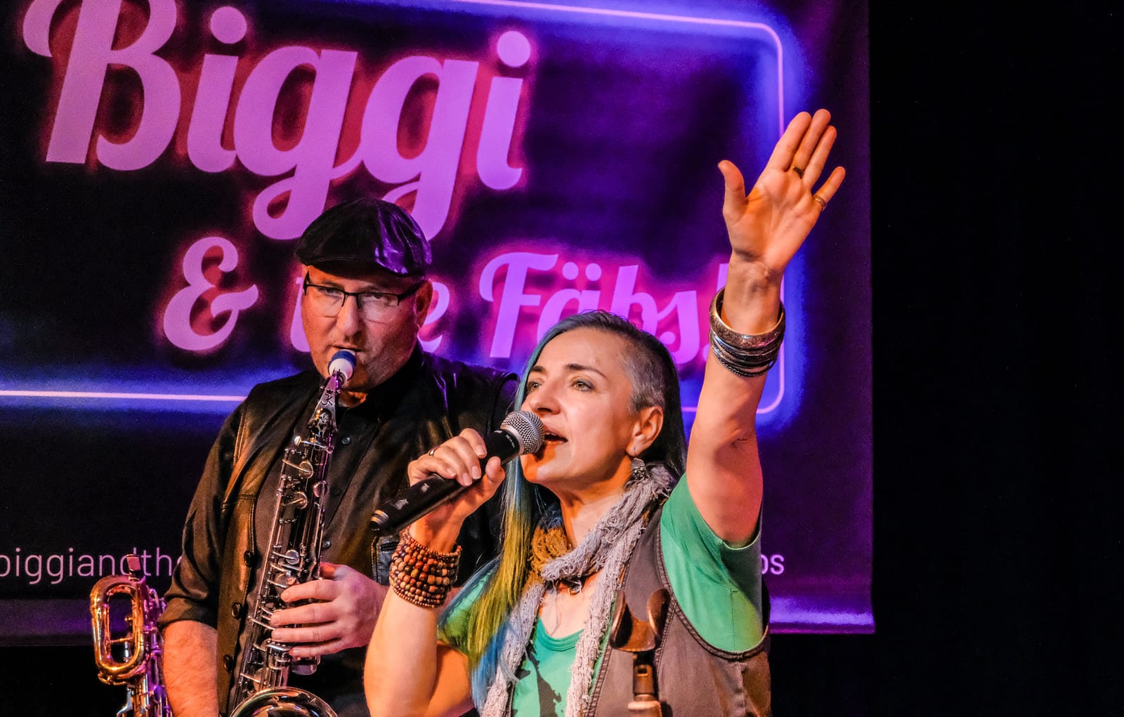Biggi Käfer mit erhobener Hand neben dem Saxofonisten von Biggi & the Fäbs!